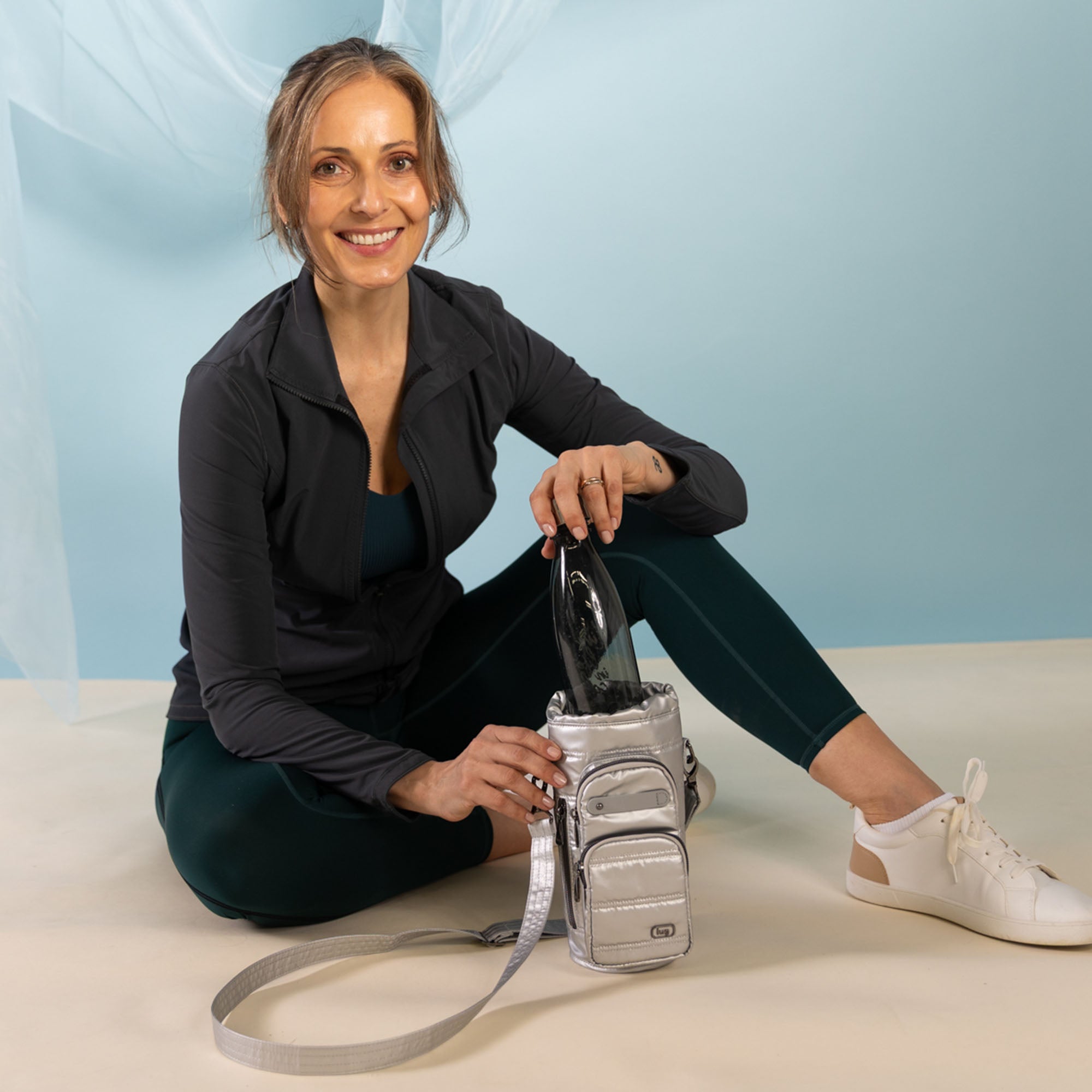 Lug Huggie Wide Crossbody Water Bottle Holder with Charm Bar in metallic silver, featuring a sleek design and adjustable strap.