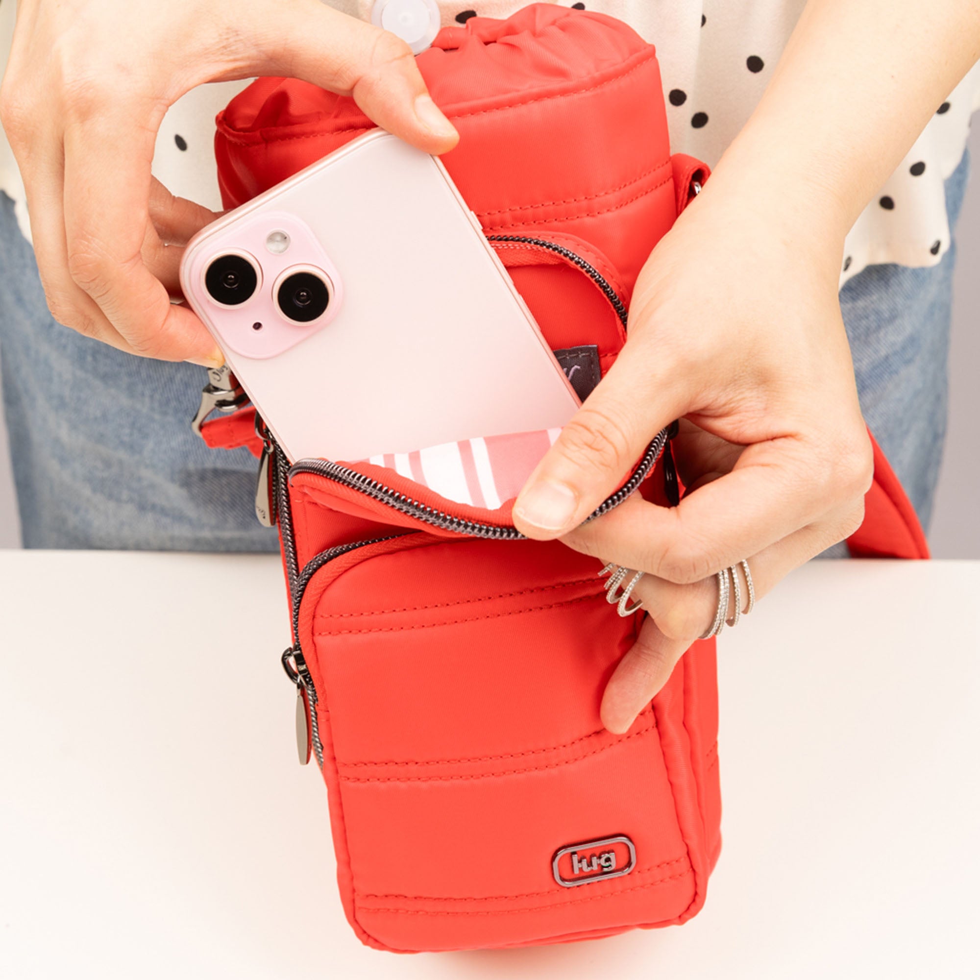 Lug Huggie Wide Crossbody water bottle holder with charm bar in Cayenne Red, worn as a stylish accessory in a lifestyle setting.