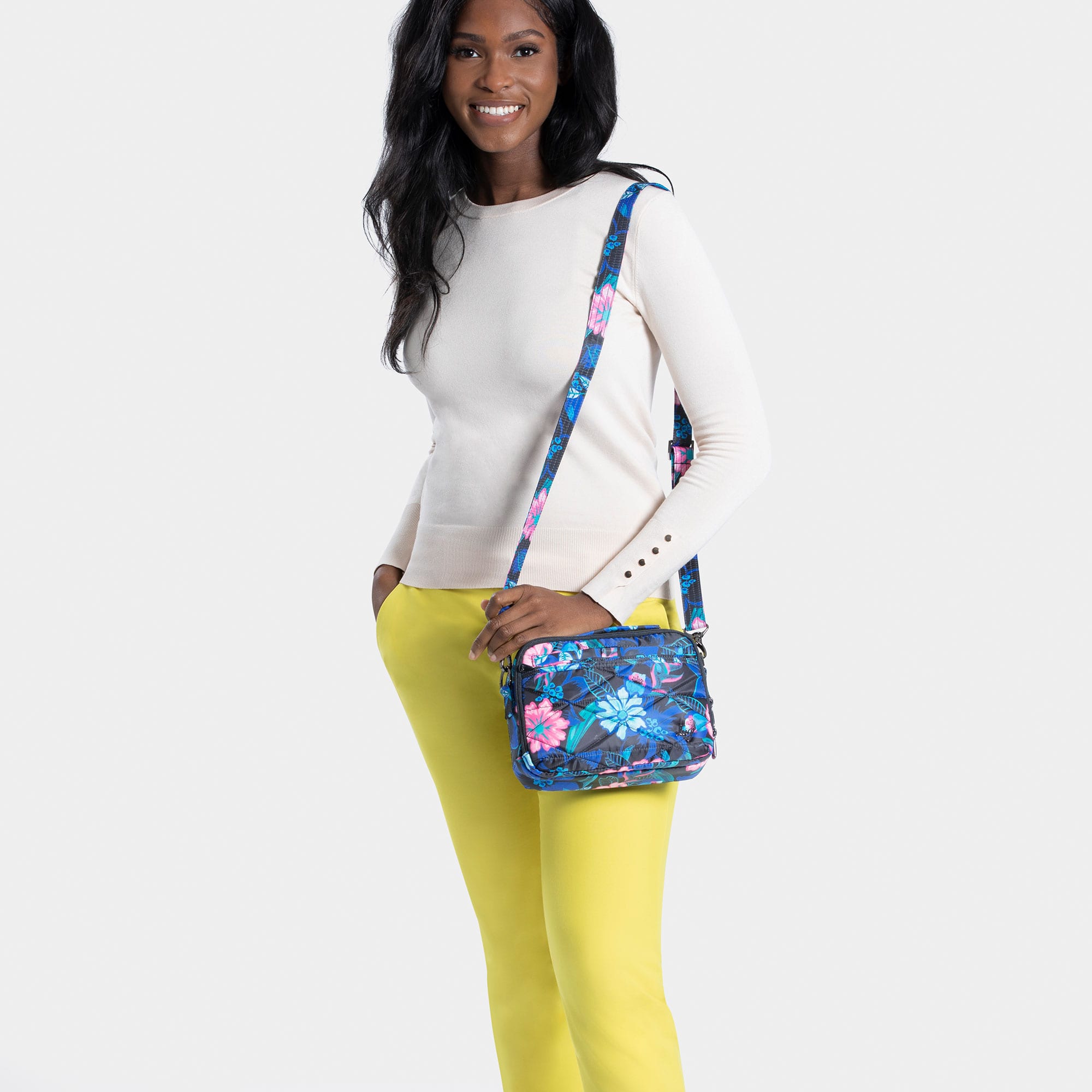 Lug Roundabout XL convertible black crossbody wallet with multiple compartments, worn by a model in a resort setting.