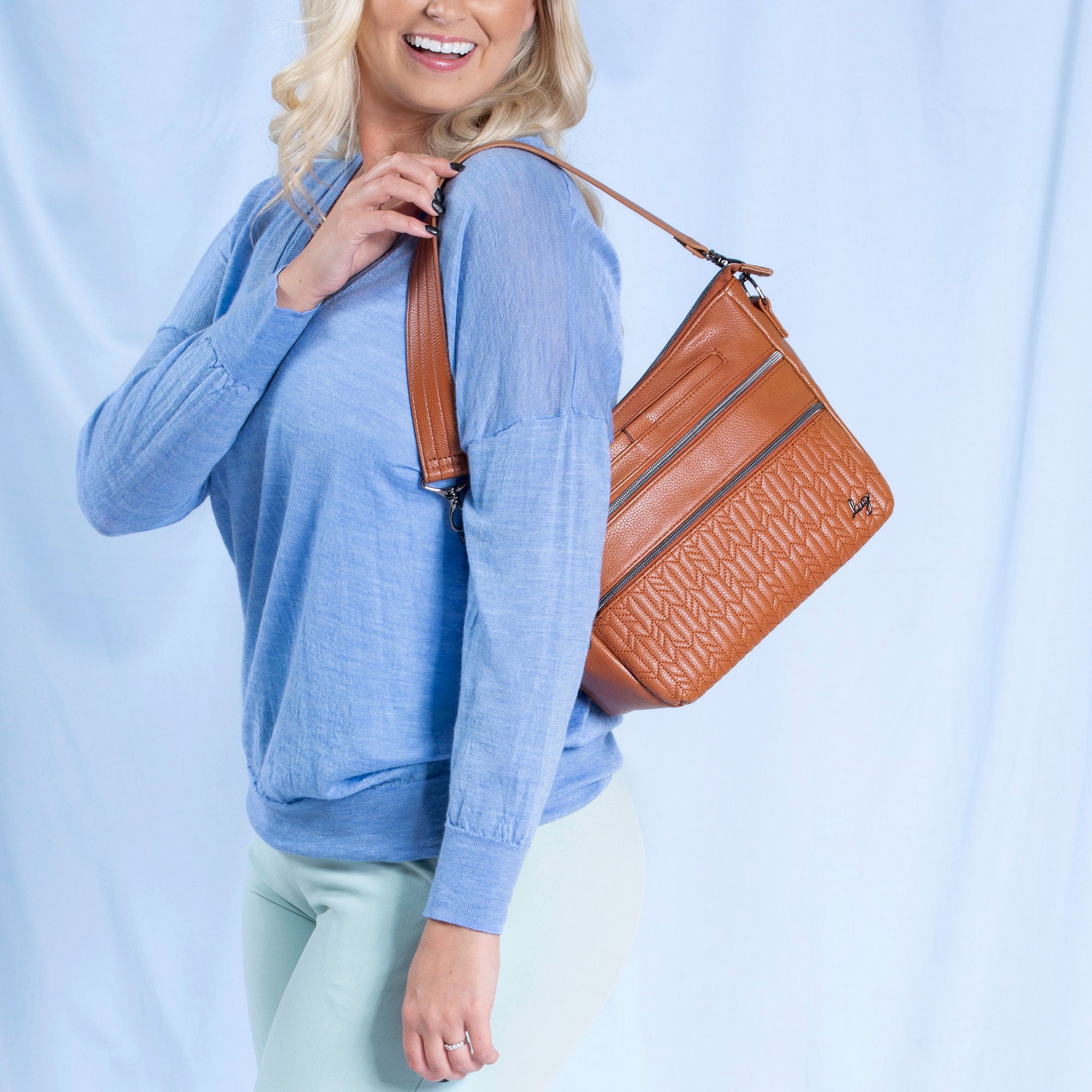 Lug Slider Classic VL crossbody bag in black leather with adjustable strap and silver hardware, displayed on a lifestyle background.